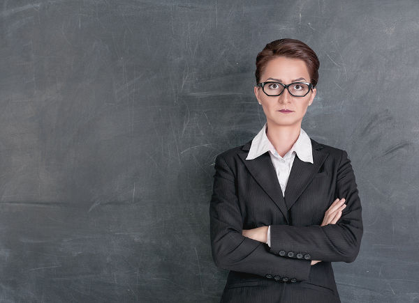 Strict teacher on the school blackboard background