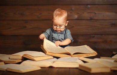 funny baby with books in glasses on a wooden background