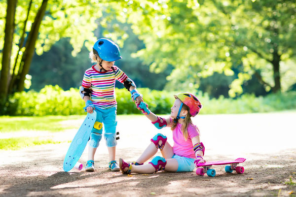 child-helping-friend-fallen-off-skateboard