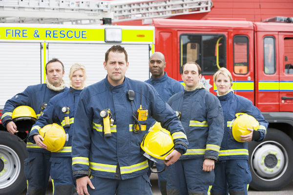 Six firefighters standing by fire engine