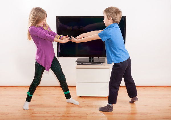 Sibling fighting over the remote controll in front of the TV