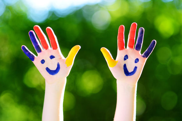 Adorable little girl with her hands painted having fun outdoors on bright summer day