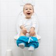 Adorable young child sitting and learning how to use the toilet