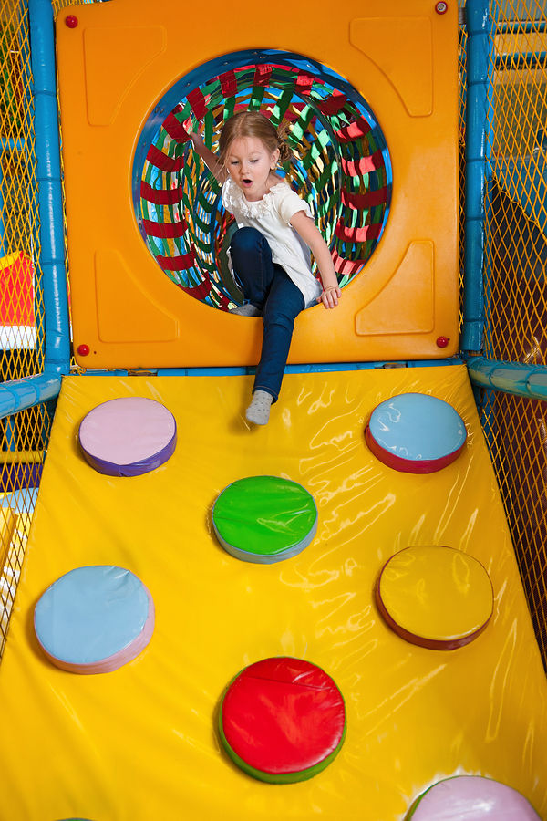 Young girl climbing down ramp in soft play centre