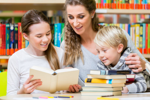 Class of children students with their teacher in the school library reading and learning