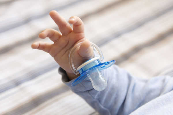 Photo of child's hand holding a pacifier, close-up