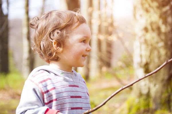 Little boy playing in the woods on a Sunny day.