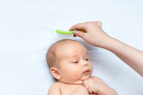 mother is brushing hair of her newborn son
