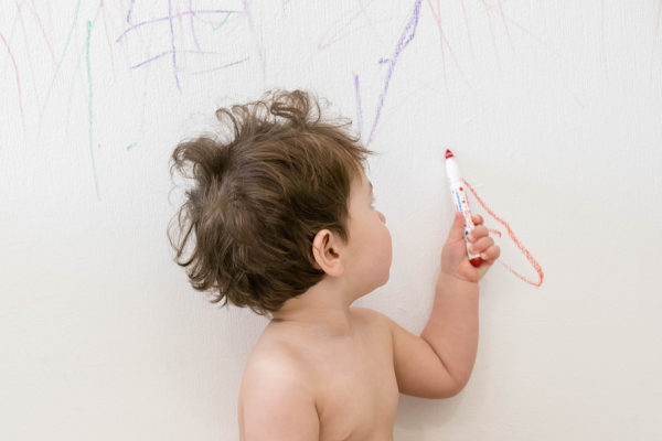 cute little baby boy drawing with crayon color on the wall. Works of child. Works of child. Caucasian brunette child 1 year old