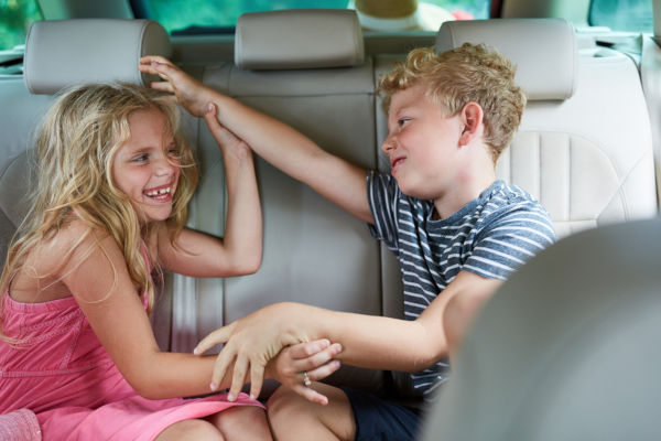 Two children are fighting and arguing with each other in the car