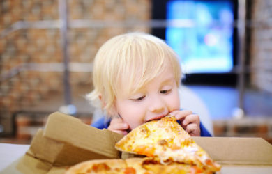 Cute Blonde Boy Eating Slice Of Pizza At Fast Food Restaurant