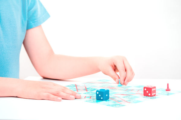 Child Plays A Board Game Snakes And Ladders With Colorful Pieces