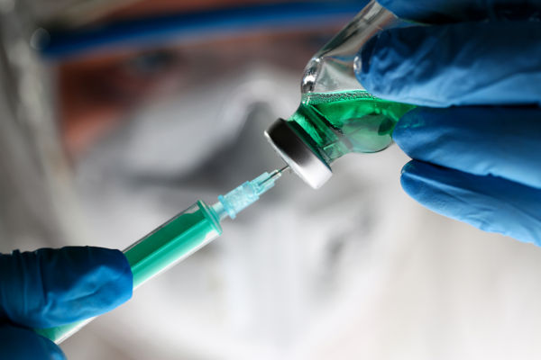 Green liquid in a vaccination vial with syringe
