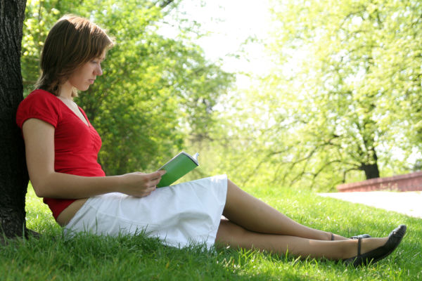 Portrait of a young woman reading book in the park