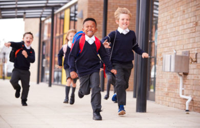 Children in school uniform running, leaving school