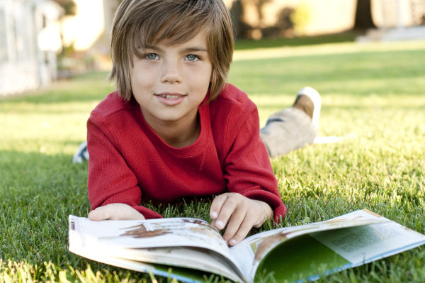 Boy lying on grass reading a book
