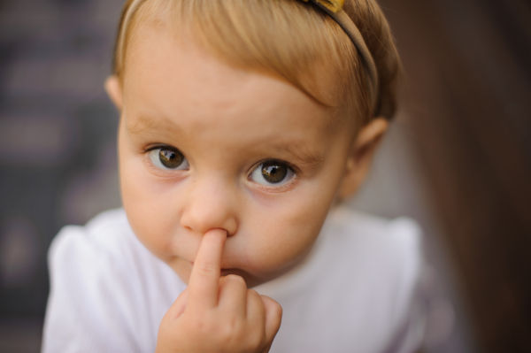 Cute little baby girl picking her nose close up