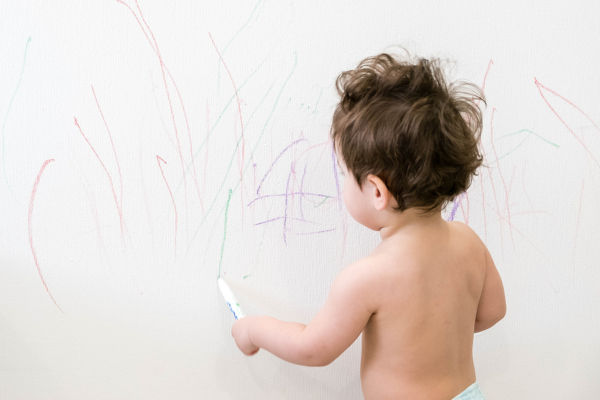 toddler drawing on the wall with lots of scribbles