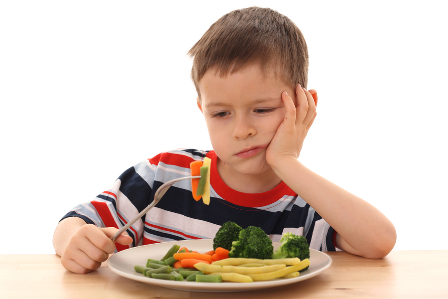 Boy with a plate of vegetables that he doesn't like