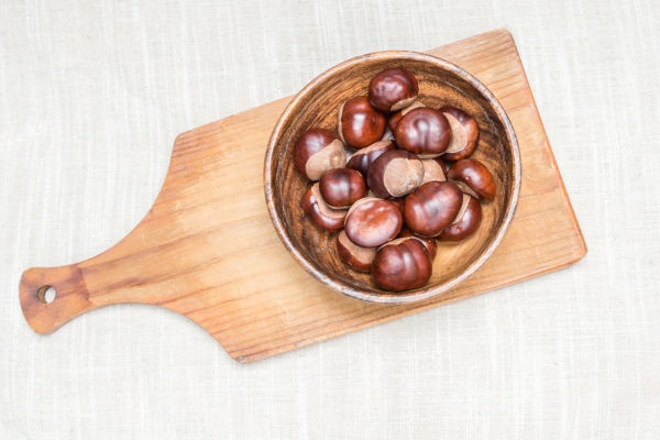 Conkers on chopping board, from a horse chestnut tree