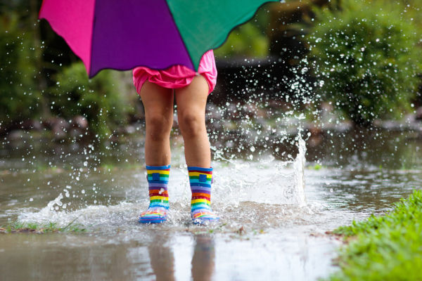 Kid With Umbrella Playing In Summer Rain.