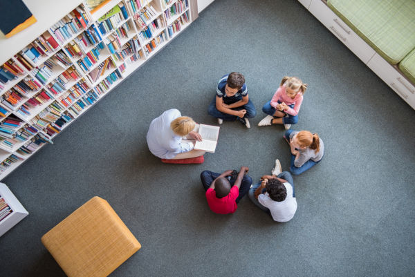 Librarian reading to children sat in a circle in library