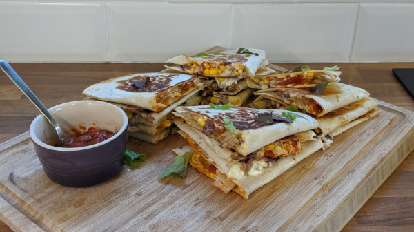 Piles of Quesadillas on a chopping board with salsa