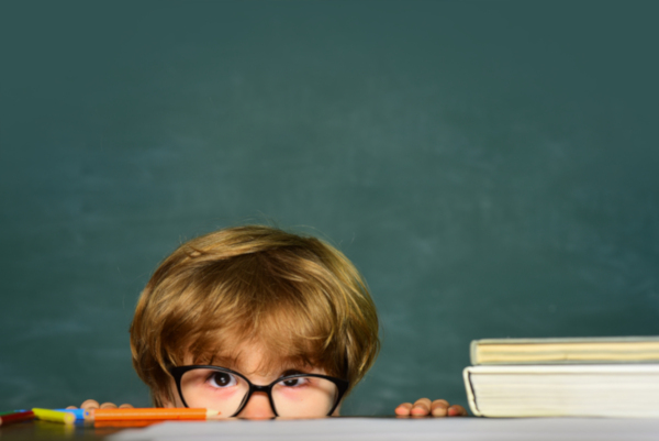 Boy peeking over the teacher's desk