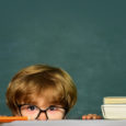 Boy peeking over the teacher's desk