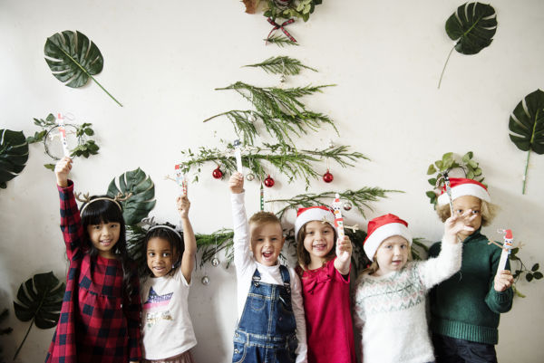 Group of children in Christmas hats by a Christmas tree