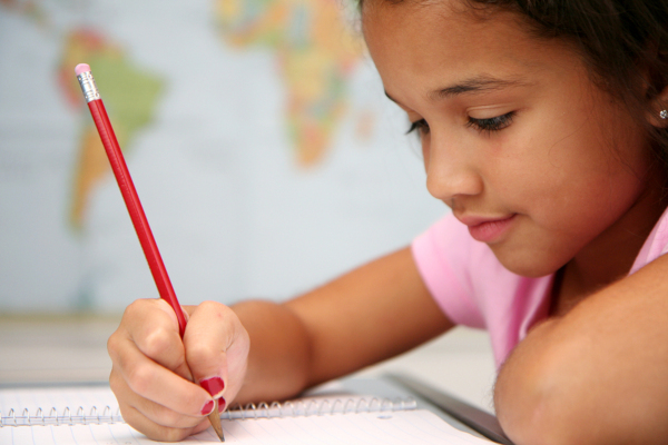 Young female child at school writing on paper
