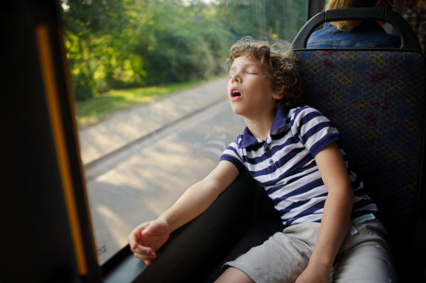 The little boy has fallen asleep in the bus. 