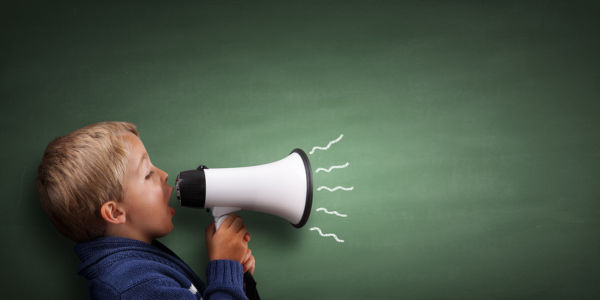 Child speaking through a megaphone against a blackboard 