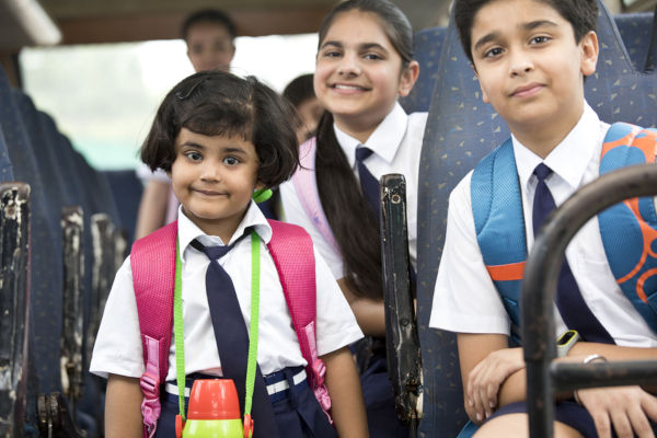 School children traveling in school bus looking at camera