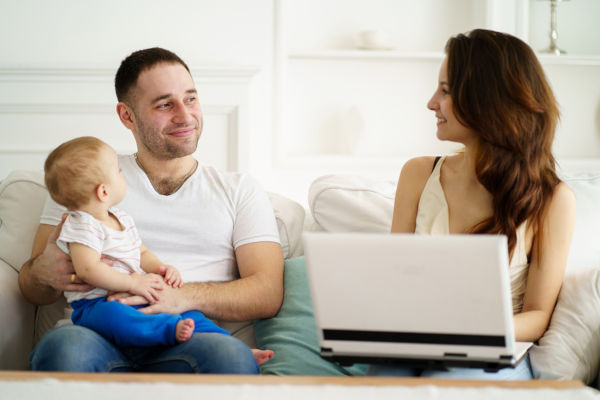 Mother working at home whilst Father holds baby