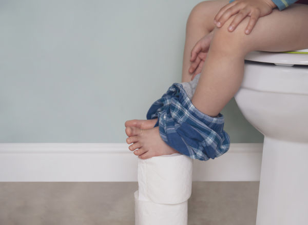Child sat on toilet with bare feet