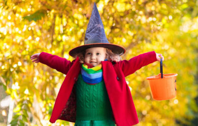 Kids trick or treat on Halloween night. Little girl with pumpkin face candy bucket. Child trick or treating.