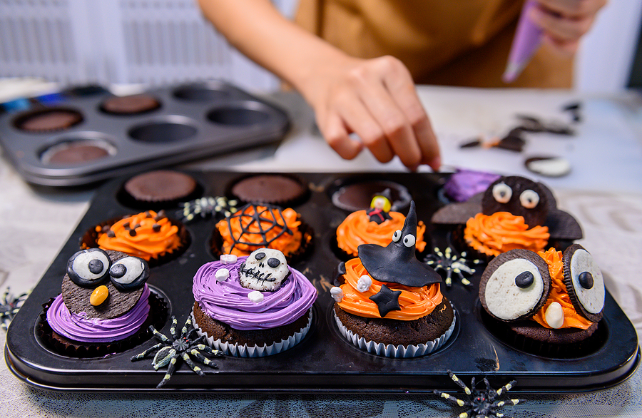 Cooking delicious homemade cake and decorate cupcake for Halloween festive. Preparing and mixing ingredients for sweet food dessert in kitchen at home.
