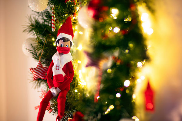Elf on the shelf wearing face mask. Christmas decoration in coronavirus pandemic. Seasonal home design in covid-19 outbreak